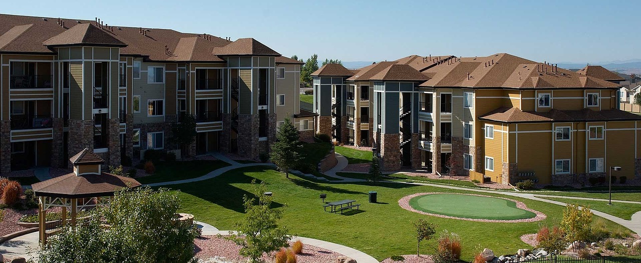 A multifamily complex, three stories high, with a green field in front.